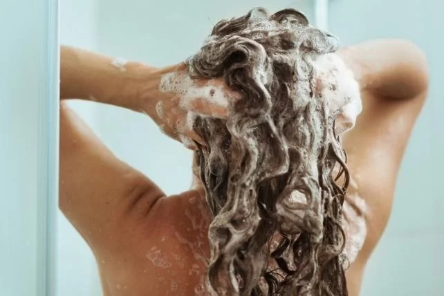 Someone rinsing shampoo from their long hair in the shower